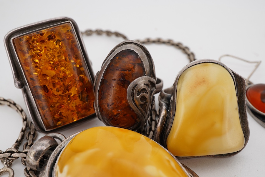 A collection of silver and amber jewels, comprising: two pairs of pendent earrings, three rings and a pendant necklace, all set with amber, mounted in silver; together with a silver and tiger's eye pendant necklace
